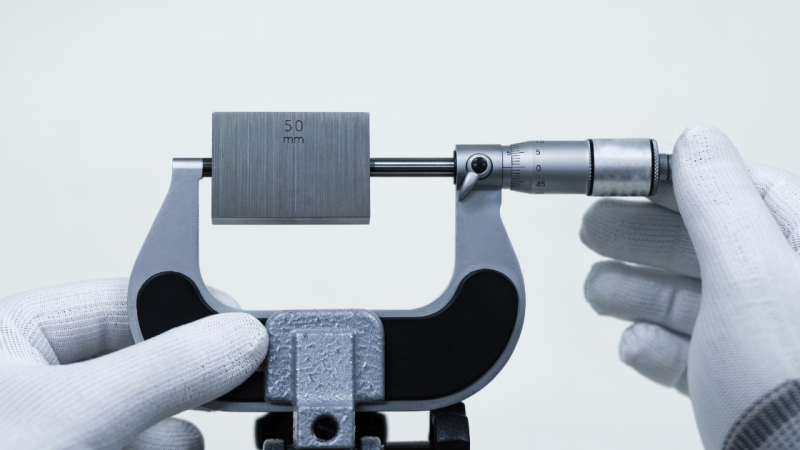 A hand holding a measuring instrument with 50mm measurement in it to highlight what is in our blog,